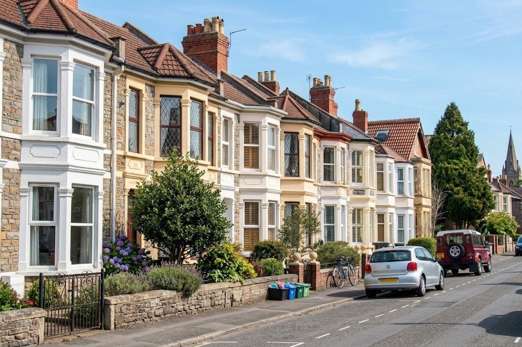 A row of period brick terraced homes on a quiet, sunny residential street in the UK
